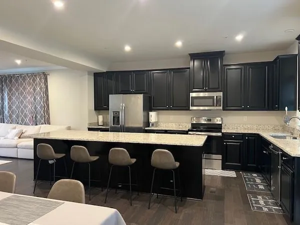 a kitchen with stainless steel appliances granite countertop a sink a stove a dining table and chairs