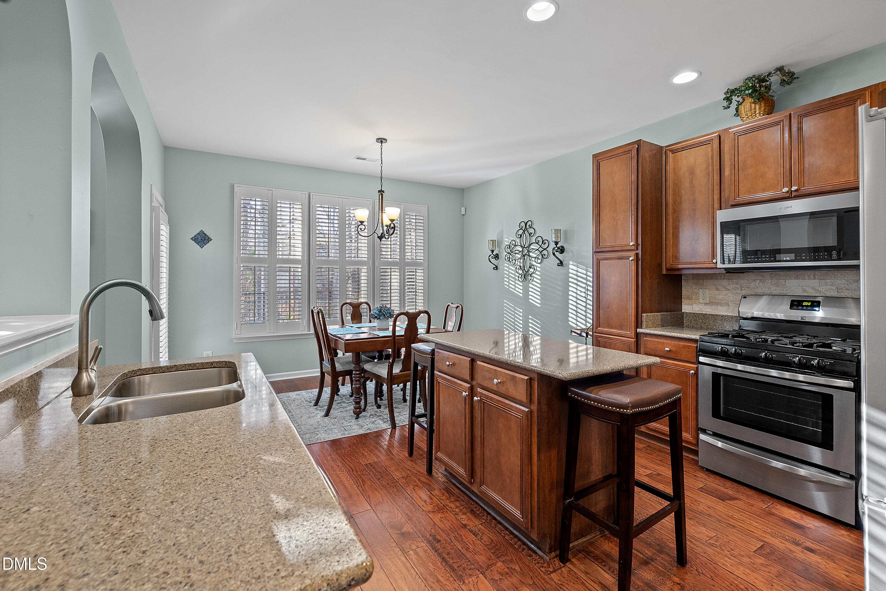 7837 Cape Charles Drive Raleigh, NC 27617 - Photo 12 of 43 a kitchen with stainless steel appliances granite countertop a stove top oven a sink dishwasher a dining table and chairs with wooden floor