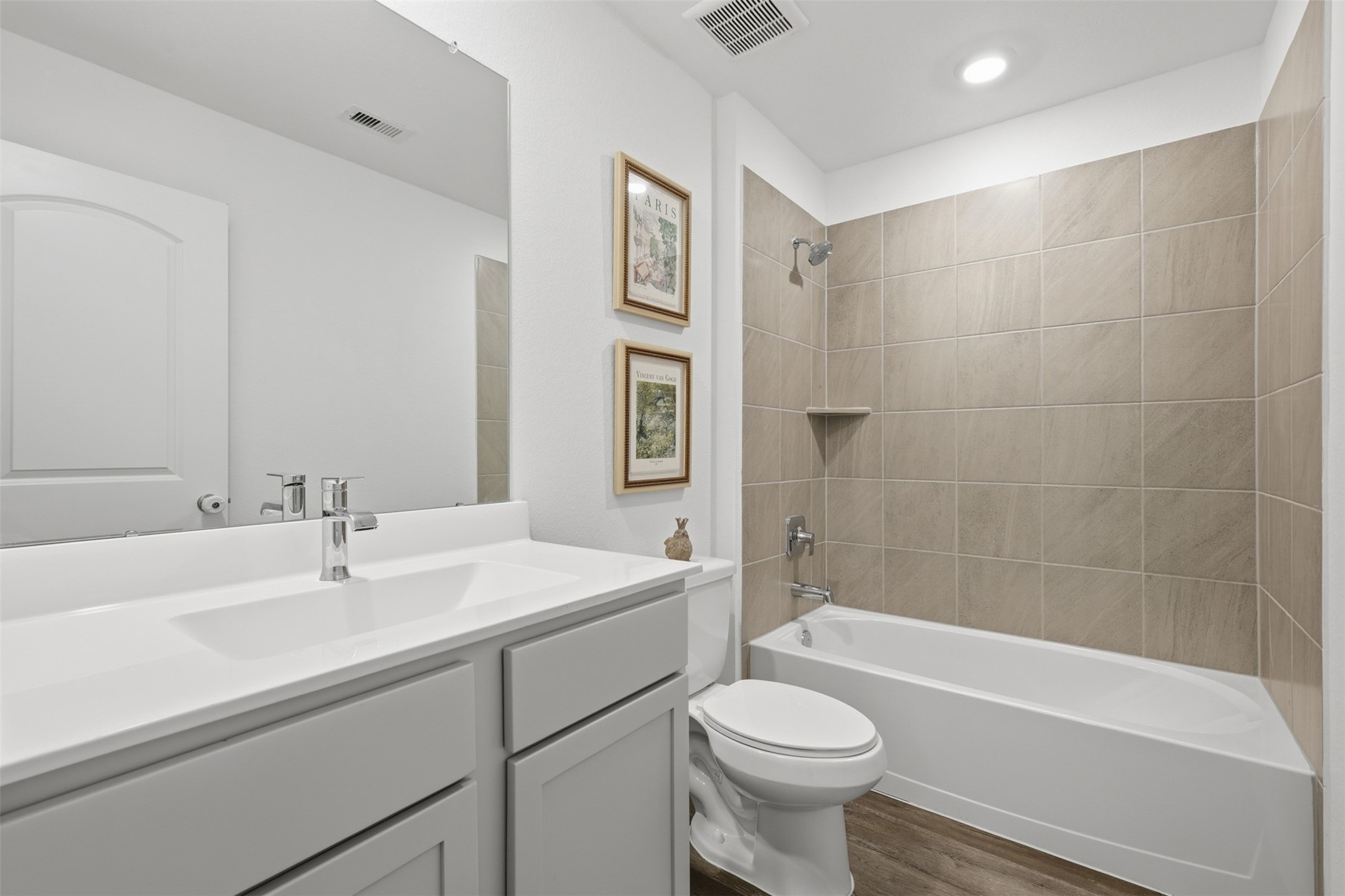 17719 Winfall Drive Crosby, TX 77532 - Photo 27 of 47 This is a modern secondary bathroom featuring a sleek vanity with a large mirror, a tiled bathtub-shower combo, and bright lighting.