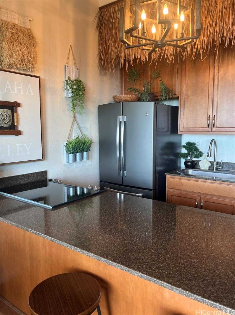 84-664 Ala Mahiku Street, Unit 194C Waianae, HI 96792 - Photo 10 of 25 a kitchen with stainless steel appliances kitchen island granite countertop a refrigerator a stove and a sink with wooden floor