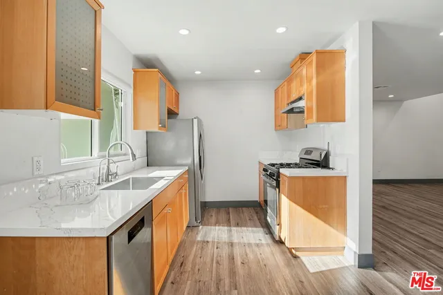 a kitchen with stainless steel appliances granite countertop a sink and wooden cabinets