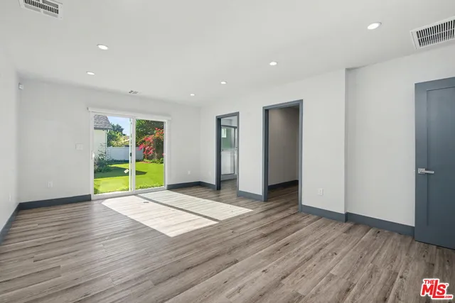 a view of an empty room with wooden floor and closet