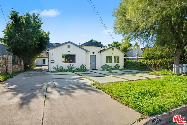 a view of a white house with a big yard plants and large trees