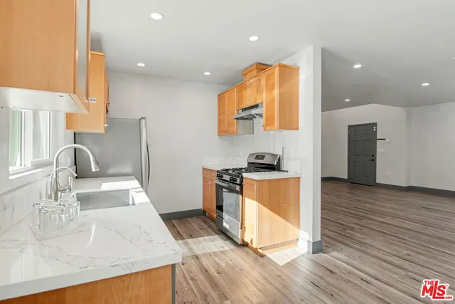 a kitchen with stainless steel appliances granite countertop a sink a stove and a wooden floors