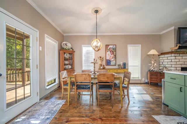 a kitchen with stainless steel appliances a dining table chairs refrigerator and cabinets