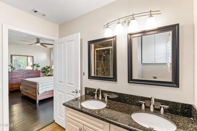 a bathroom with a granite countertop double vanity sink and a mirror