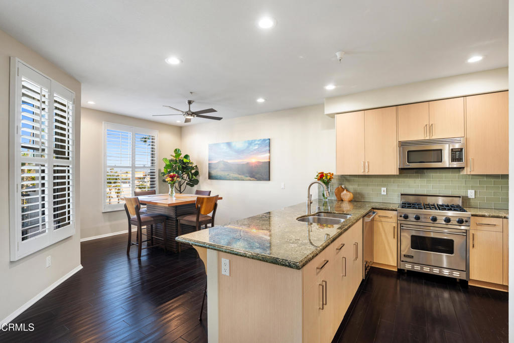 436 Poli Street, Unit 404 Ventura, CA 93001 - Photo 8 of 32 a kitchen with stainless steel appliances granite countertop a stove top oven a sink dishwasher a dining table and chairs with wooden floor