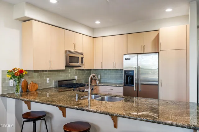 a kitchen with stainless steel appliances granite countertop a sink refrigerator and microwave