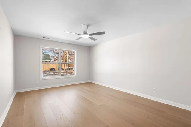 an empty room with wooden floor and ceiling fan