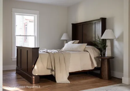a bed sitting in a bedroom next to a window and a potted plant