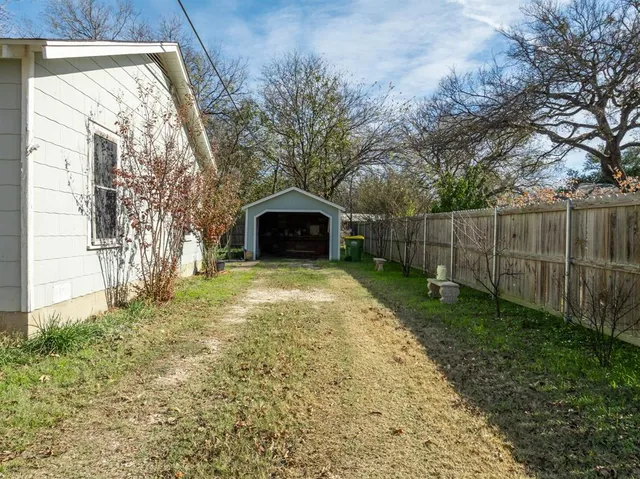 a view of a backyard with large trees and wooden fence