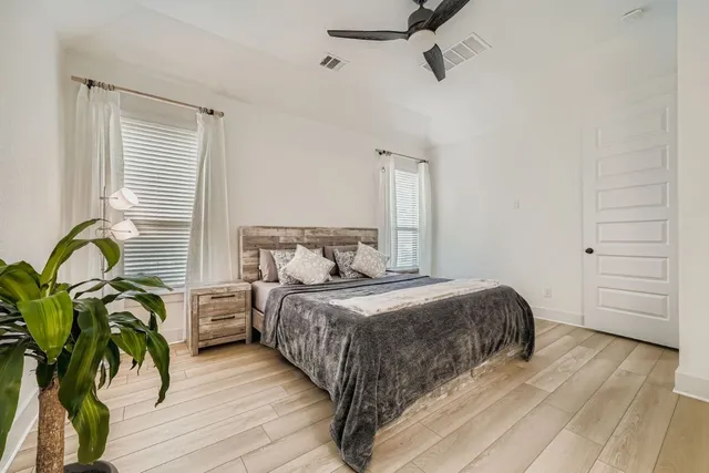a bedroom with a bed potted plant with the dresser