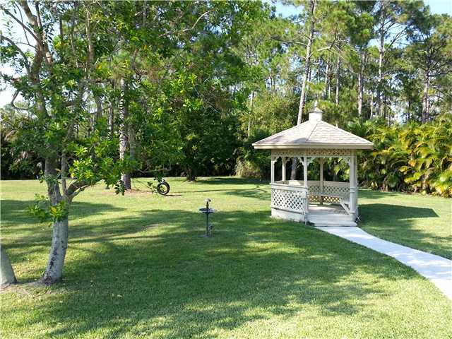 12757 Sandy Run Road Jupiter, FL 33478 - Photo 22 of 25 a front view of a house with garden and trees