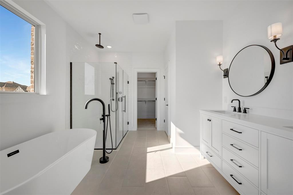 1014 Butterfly Lane Justin, TX 76247 - Photo 13 of 40 a bathroom with a double vanity sink a mirror and a bathtub