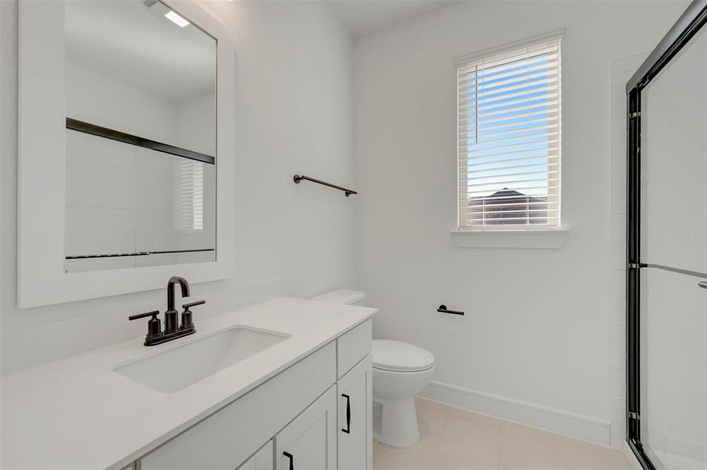 1014 Butterfly Lane Justin, TX 76247 - Photo 19 of 40 a bathroom with a sink a toilet and a mirror