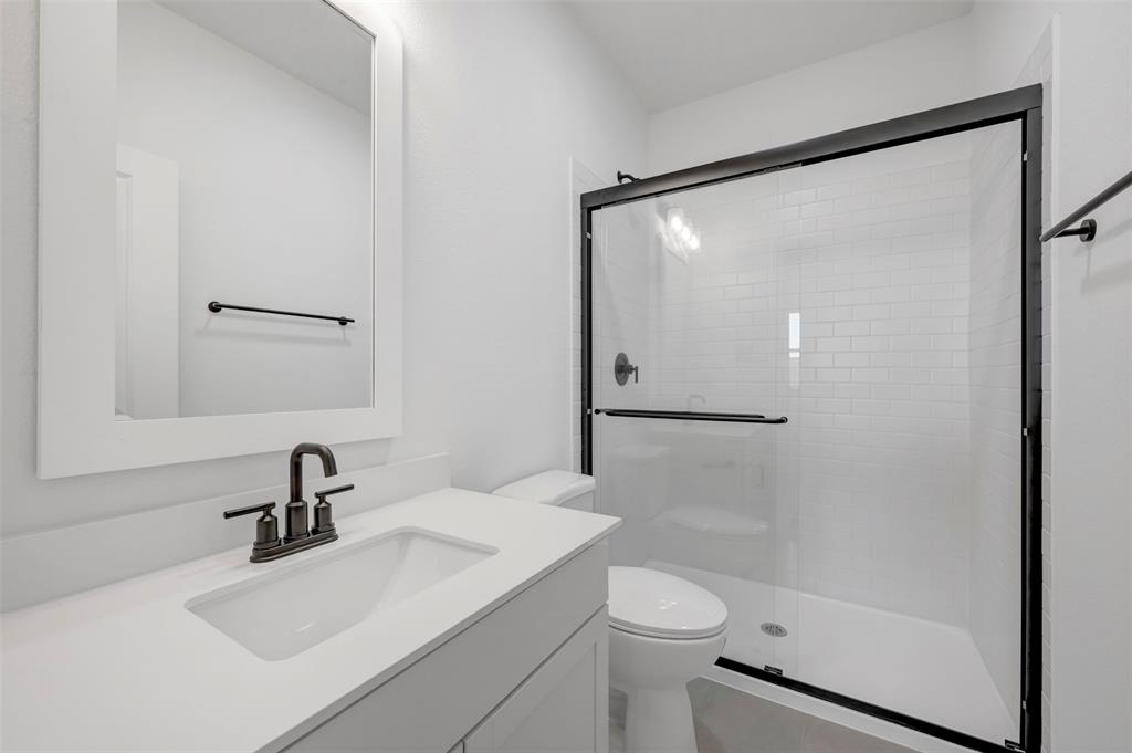 1014 Butterfly Lane Justin, TX 76247 - Photo 22 of 40 a bathroom with a sink mirror toilet and shower