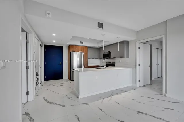 a large white kitchen with kitchen island a sink stainless steel appliances and cabinets