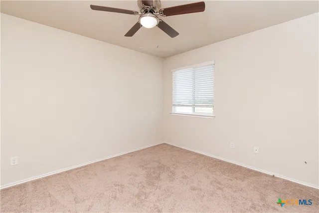 an empty room with a window and a ceiling fan