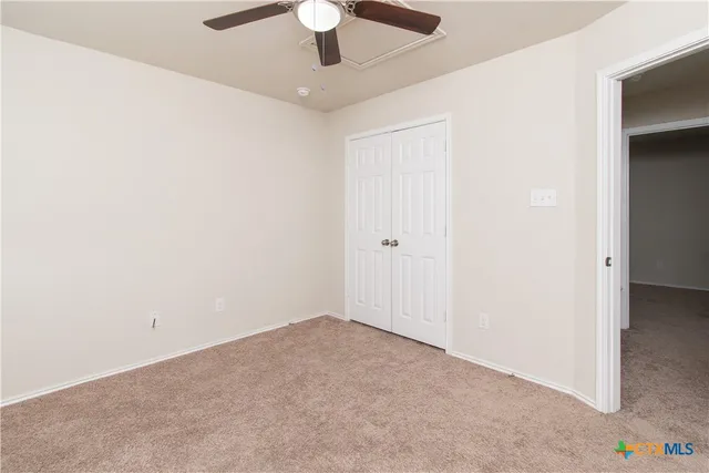 an empty room with a ceiling fan and a window