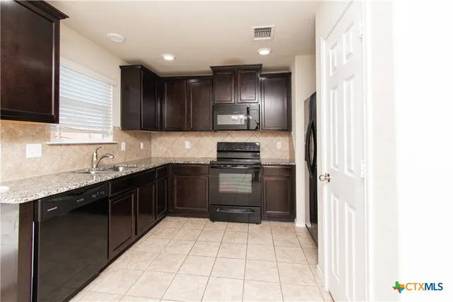 a kitchen with stainless steel appliances granite countertop a refrigerator and a sink
