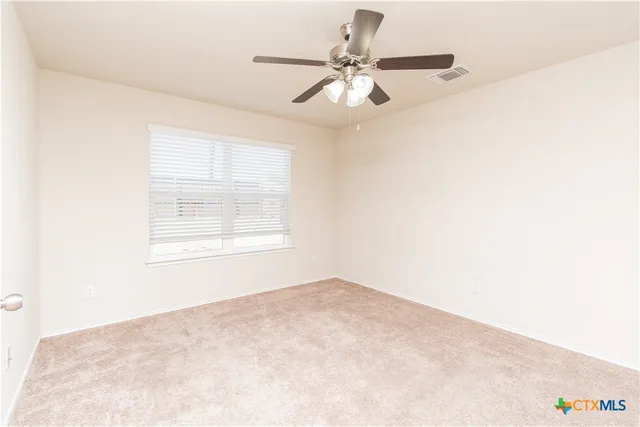 an empty room with a window and a fan
