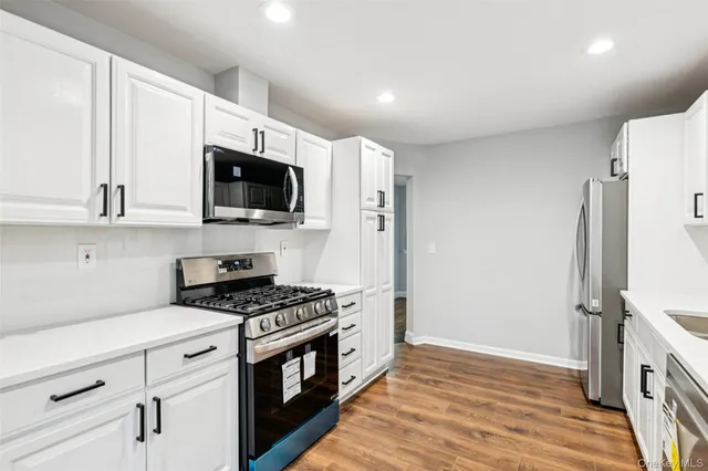 a kitchen with stainless steel appliances white cabinets and a stove top oven