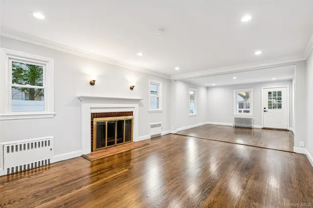 an empty room with wooden floor fireplace and windows