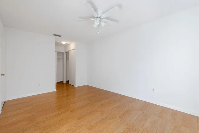 an empty room with a fan & a ceiling fan