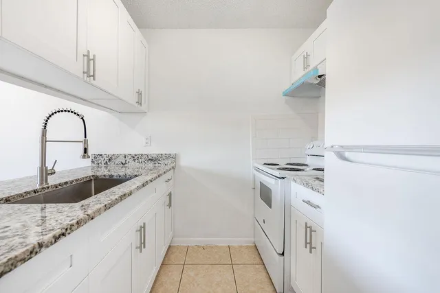 a kitchen with granite countertop a sink and a stove