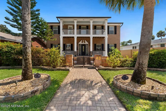 a front view of a house with a yard and potted plants