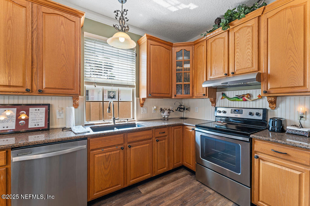 43 Valencia Street St. Augustine, FL 32084 - Photo 18 of 48 a kitchen with stainless steel appliances granite countertop a stove a sink dishwasher and microwave with wooden cabinets