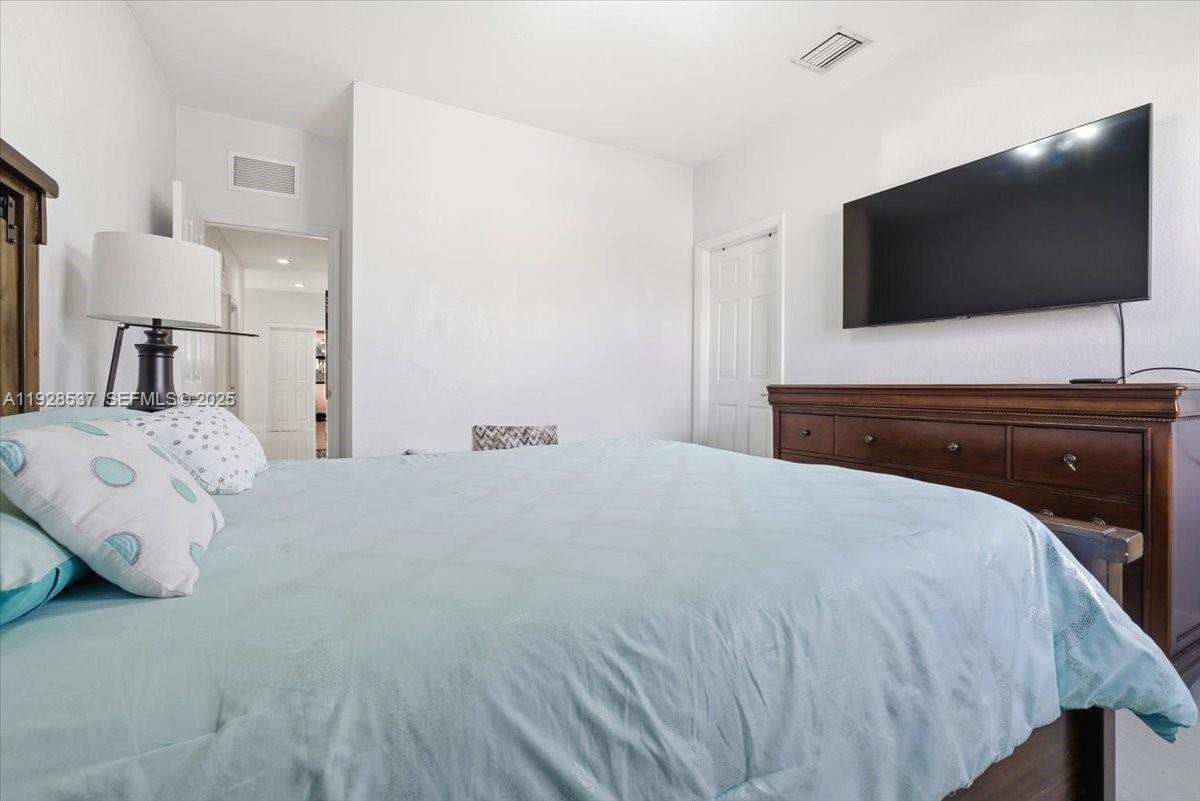 3522 West 86th Terrace Hialeah, FL 33018 - Photo 24 of 35 a bedroom with a bed and a flat tv screen on wall