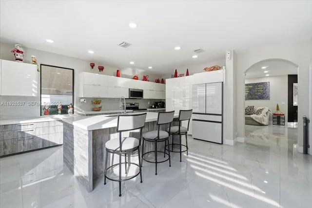 a open kitchen with stainless steel appliances kitchen island granite countertop a table and chairs in it