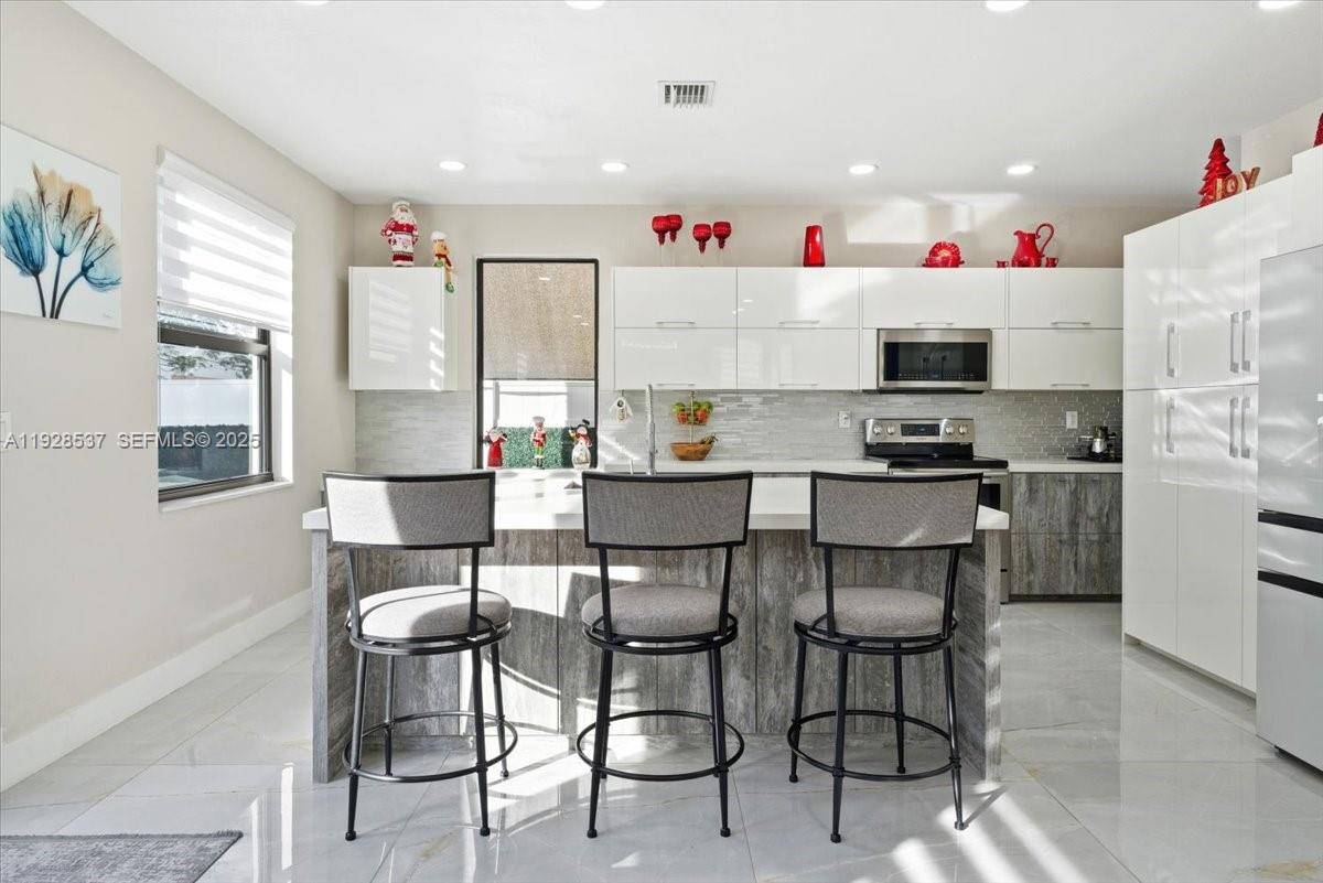 3522 West 86th Terrace Hialeah, FL 33018 - Photo 7 of 35 a open kitchen with stainless steel appliances kitchen island granite countertop a table and chairs in it