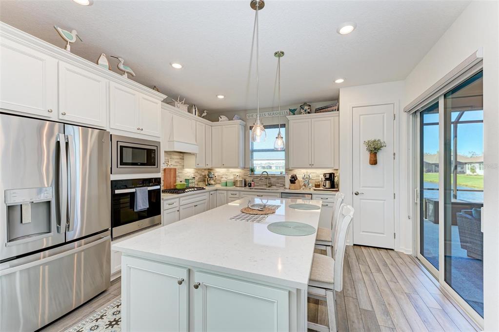 9272 Ballaster Pointe Loop Parrish, FL 34221 - Photo 16 of 79 a kitchen with stainless steel appliances a stove a sink a refrigerator white cabinets and wooden floor