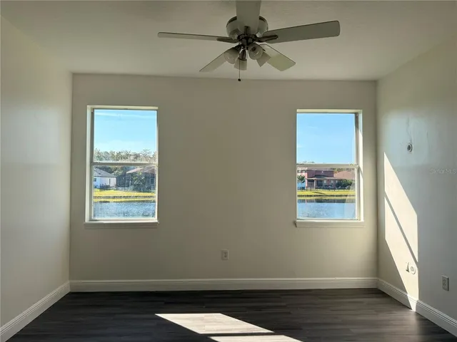 a view of an empty room with a window and wooden floor