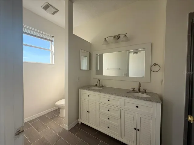 a bathroom with a granite countertop sink mirror and toilet