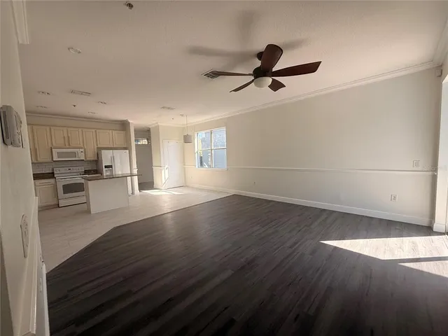 a view of a kitchen with wooden floor electronic appliances and cabinets