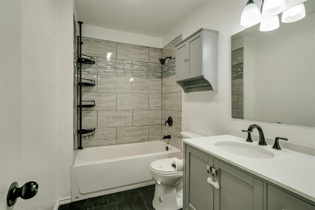 400 South Bailey Street Electra, TX 76360 - Photo 25 of 36 a bathroom with a toilet a sink a mirror a bathtub and shower