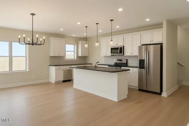 a kitchen with stainless steel appliances granite countertop a refrigerator a sink a stove and a microwave