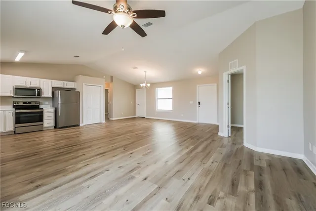 a view of empty room with wooden floor and ceiling fan
