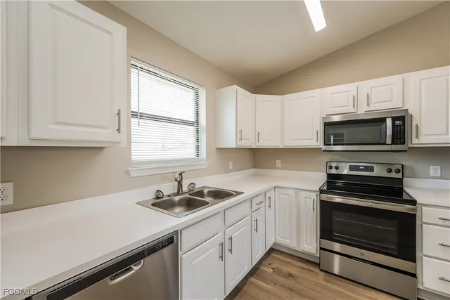 a kitchen with white cabinets appliances and window