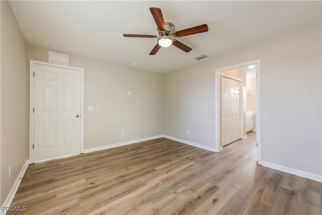 an empty room with wooden floor fan and windows