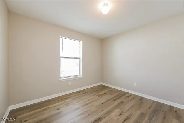 an empty room with wooden floor and window