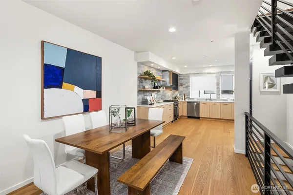 a living room with stainless steel appliances furniture a rug and a kitchen view