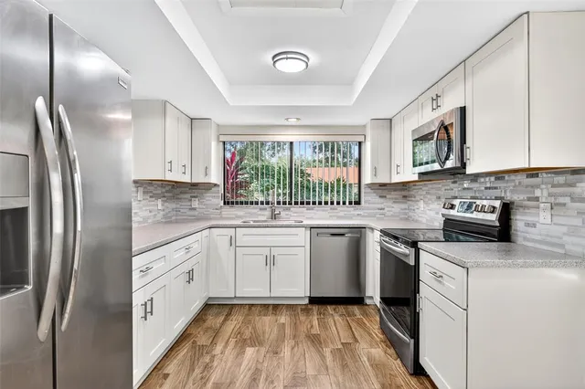 a kitchen with white cabinets and window