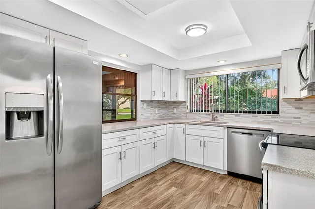 a kitchen with a sink appliances cabinets and a large window