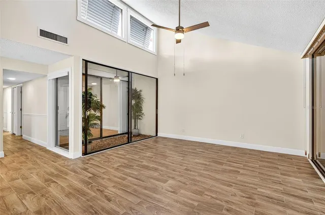 a view of empty room with wooden floor and fan