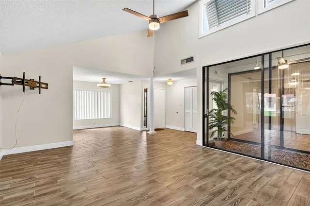 a view of an empty room with wooden floor and a window