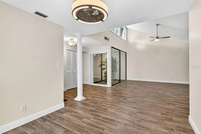 a view of an empty room with wooden floor and a window